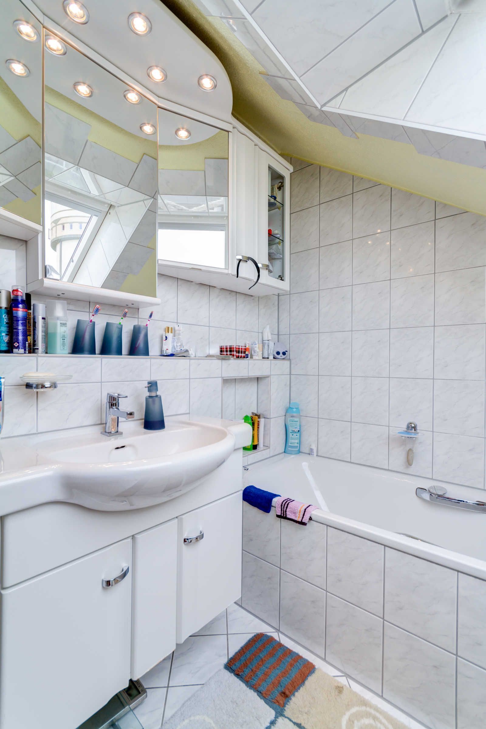 Een moderne badkamer met een witte wastafel, spiegel en bad.