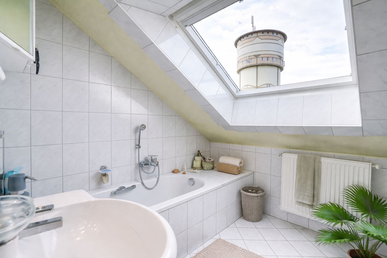 Een moderne badkamer met dakraam, ligbad, wastafel en toilet.