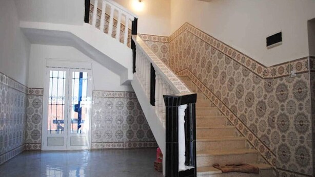 A spacious interior with a grand staircase, patterned walls, and a reflective floor. - Apartment 3 combining countryside and sea (Hadjadj)