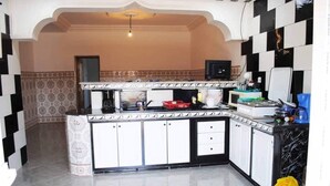 A compact kitchen with a black and white checkered backsplash, a built-in stove, and a microwave. - Apartment 3 combining countryside and sea (Hadjadj)