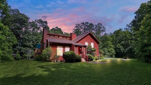 Uma casa vermelha com um gramado bem cuidado e um caminho que leva à entrada.
