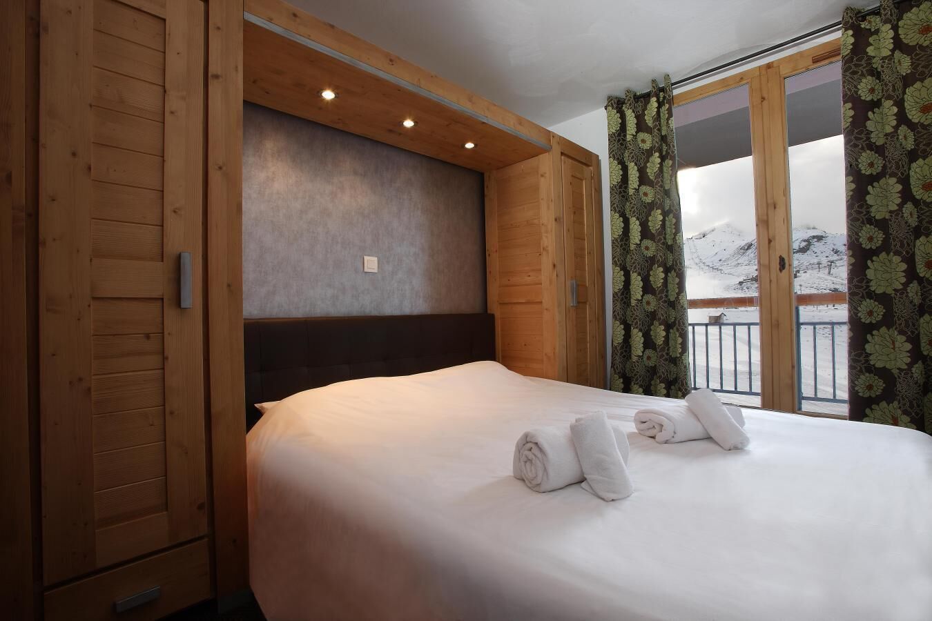 Une chambre d’hôtel avec un grand lit, des murs en bois et une vue sur des montagnes enneigées.