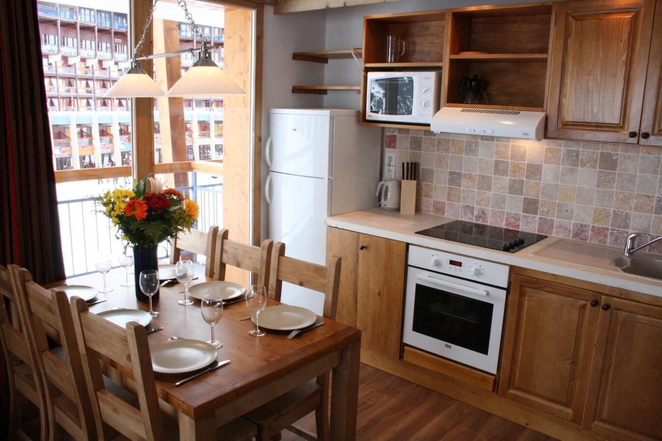 A compact kitchen with wooden cabinets, a white refrigerator, a microwave, a stove, and a sink.