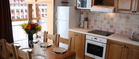 A compact kitchen with wooden cabinets, a white refrigerator, a microwave, a stove, and a sink.