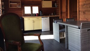 Cucina accogliente in stile chalet con pareti in legno, zona pranzo con mobili in vimini e una sola sedia.