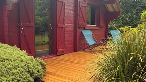 Un edificio in legno rosso con una terrazza in legno e due sedie blu.
