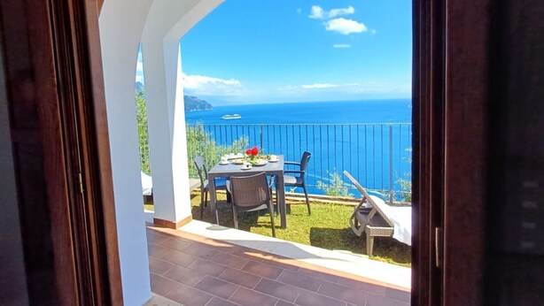 A view from a balcony with a table and chairs, overlooking a body of water and a distant landmass. - Minerva di Lone at 3 kms from Amalfi (Amalfi)