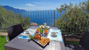 A table set for breakfast with croissants, pastries, and orange juice on a balcony overlooking the sea. - Minerva di Lone at 3 kms from Amalfi (Amalfi)