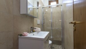 A bathroom with a glass-enclosed shower, a white sink, and a mirror above it. - Minerva di Lone at 3 kms from Amalfi (Amalfi)