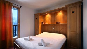 Un dormitorio con una cama grande, un armario de madera y una ventana con cortinas.