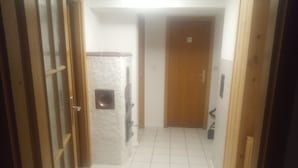 A narrow hallway with a tiled floor, a wooden door at the end, and a wall-mounted light fixture. - Nice newly renovated apartment in a quiet location !! (Wald)