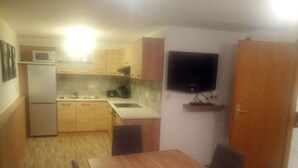 A compact kitchen with a refrigerator, microwave, sink, and a flat-screen TV mounted on the wall. - Nice newly renovated apartment in a quiet location !! (Wald)