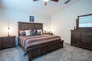 Ein Schlafzimmer mit einem hölzernen Bett, Nachttischen, einer Kommode und einem Deckenventilator.