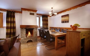 A cozy dining area with a stone fireplace, wooden furniture, and a chandelier. - Wifi, 50m from resort center, fitness, swimming pool, sauna, hammam, balcony, tv, ski locker, 32m² (Oz)