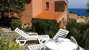 Un edificio con tetto in tegole rosse, poltrone bianche e un tavolo.