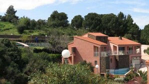 Un edificio a due piani con tetto in tegole rosse, una piscina e un'antenna parabolica.