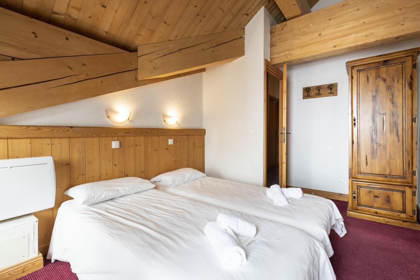 Ein Schlafzimmer mit Holzboden, einem Bett mit weißen Leinentüchern und einem Holzschrank.