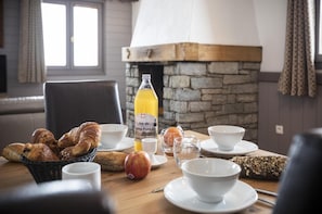 A breakfast setting with croissants, an apple, juice, and bowls on a wooden table. - Wifi, 200m from resort center, fitness, swimming pool, sauna, balcony, fireplace or stove, tv (Val Thorens)