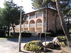 Um edifício de vários andares com um pátio central, rodeado por árvores e arbustos.