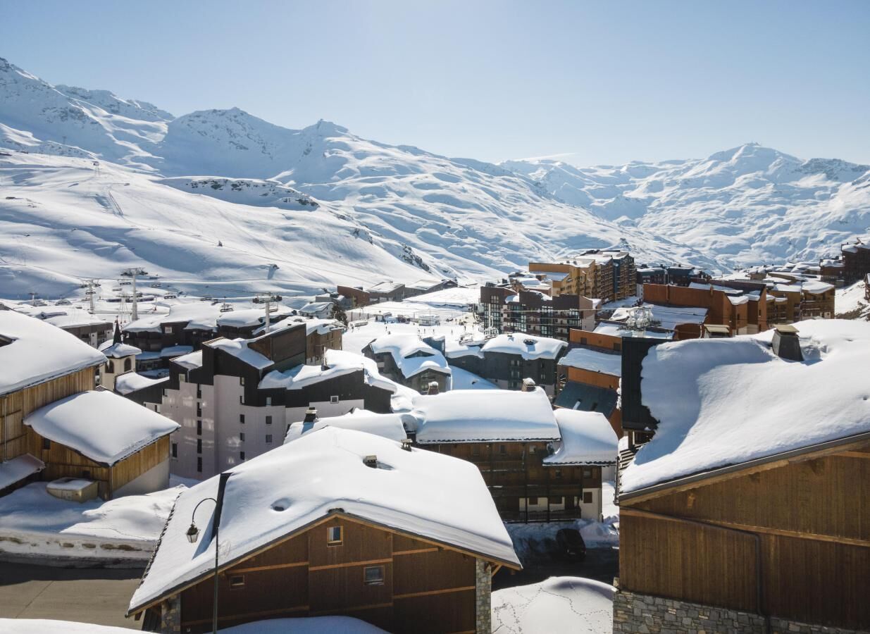 A snow-covered town with wooden buildings and a mountain backdrop.