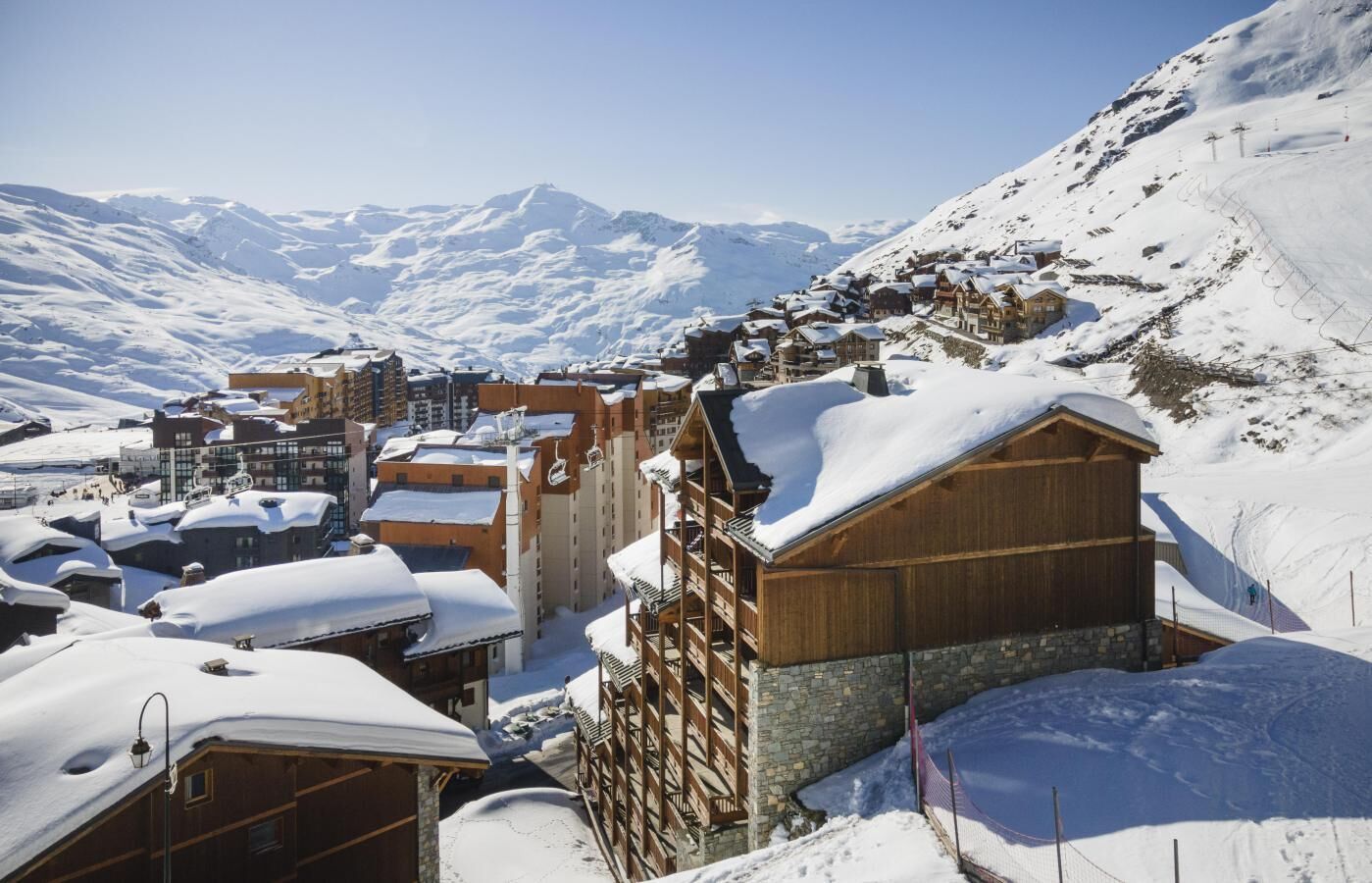 A snow-covered mountain village with wooden buildings and a ski slope.