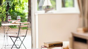 An open book on a wooden table, a chair, and a table with a glass of red wine and a loaf of bread. - A lovely, modern apartment just 350 yards from the beach. (St Margaret&rsquo;s Bay)