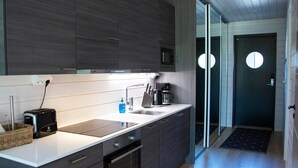 Una cocina moderna con armarios oscuros, encimera blanca, horno empotrado, microondas y cafetera.