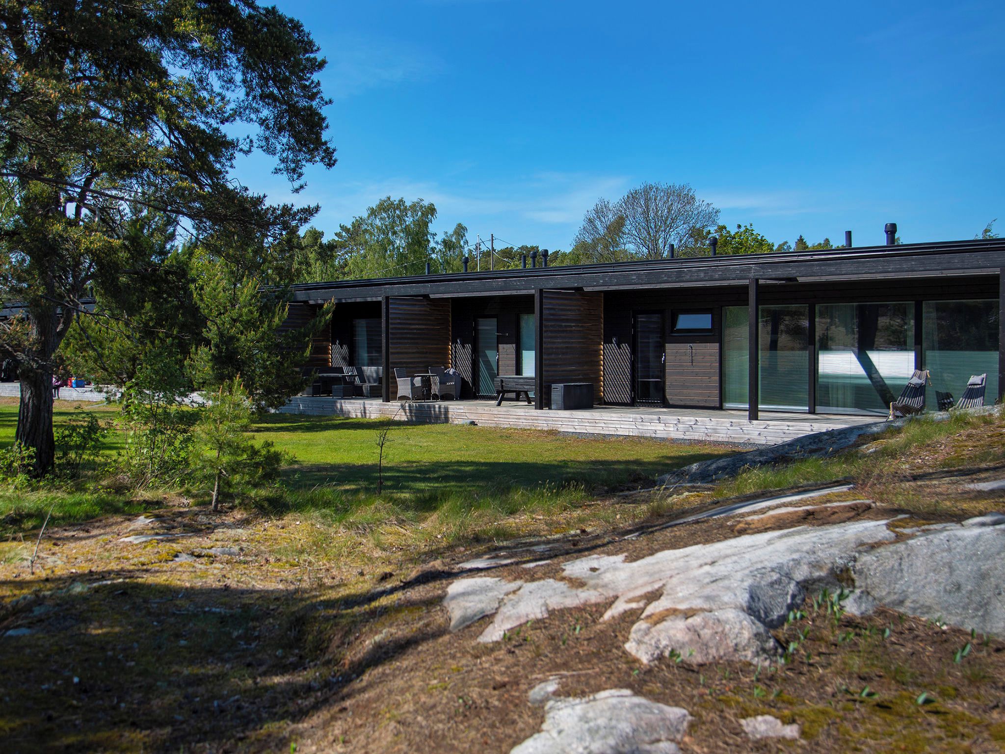 Et moderne hus med terrasse, udendørs møbler og udsigt over det omkringliggende landskab.