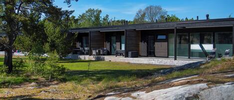 Et moderne hus med terrasse, udendørs møbler og udsigt over det omkringliggende landskab.