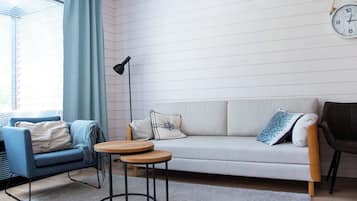 Uma sala de estar moderna com sofá, duas poltronas, uma mesa de centro e um abajur.