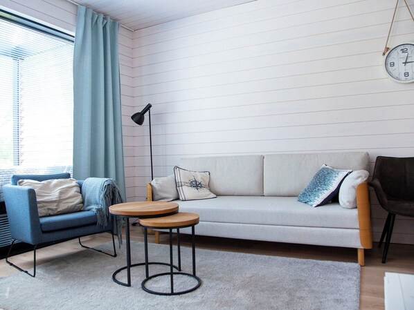 Ett modernt vardagsrum med en soffa, två fåtöljer, ett soffbord och en golvlampa.