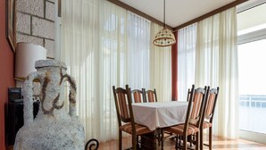Un coin repas avec une table dressée pour quatre personnes, entourée de chaises, d’un vase décoratif en pierre et d’un luminaire suspendu.