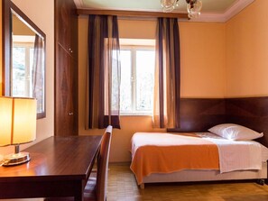 A hotel room with a bed, a desk, and a lamp.