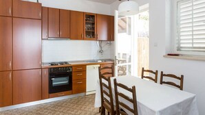Une cuisine compacte dotée de meubles en bois, d’un lave-vaisselle et d’un coin repas avec une table et des chaises.