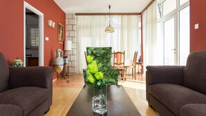 Un salon comprenant deux canapés, une table basse, un fauteuil à motifs et un coin repas avec des chaises et une table.