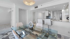 Un comedor moderno con una mesa de vidrio, sillas blancas y una lámpara circular original.