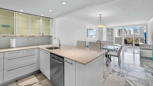 Una cocina moderna con una isla central, armarios blancos y un amplio ventanal con vistas a la ciudad.