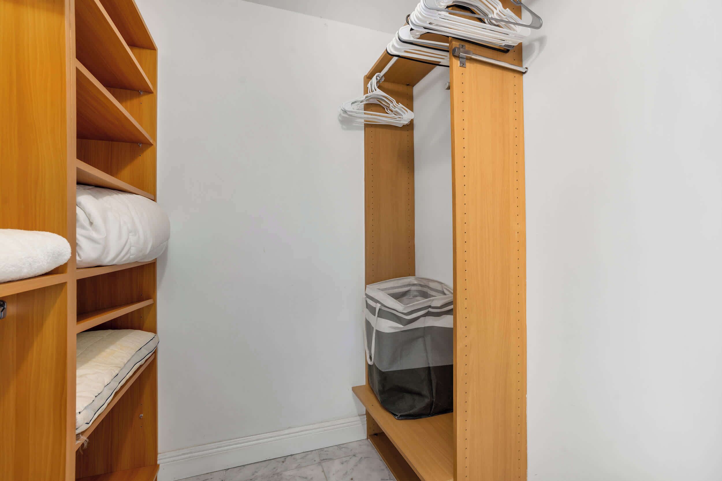 A wooden closet with shelves, a hanging rod, and a bench.