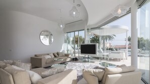 Una sala moderna con un televisor de pantalla plana grande, sofás color beige y una mesa de centro de vidrio.