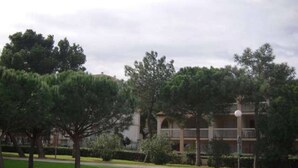 Un edificio de varios pisos con un patio central, rodeado de árboles y un césped bien cuidado.
