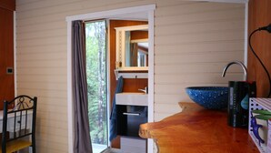 Une cuisine de taille réduite, dotée d’un plan de travail en bois, d’un évier et d’une fenêtre agrémentée de rideaux.