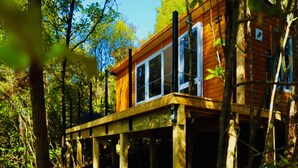 Une cabane en bois dotée d’une terrasse, entourée d’arbres.