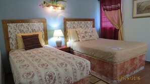 Un lit double avec une literie à motifs floraux et une table de chevet avec une lampe.
