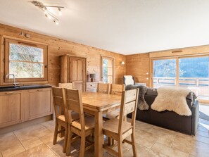 A wooden interior with a dining table, chairs, a sofa, and large windows. - 3* Apartment, cozy, 8 pers, La Clusaz, WIFI (La Clusaz)