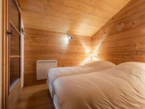 A wooden cabin room with two beds, a heater, and a wall-mounted lamp. - 3* Apartment, cozy, 8 pers, La Clusaz, WIFI (La Clusaz)