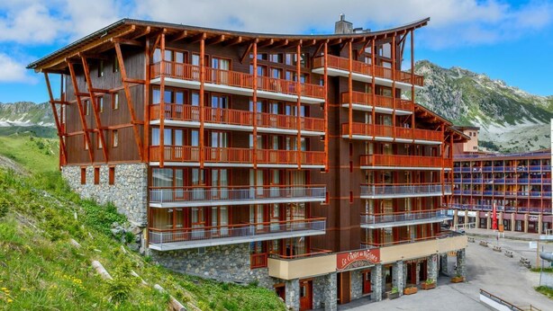 A multi-story hotel with balconies, stone facade, and a mountain backdrop. - Wifi, ski-in/ski-out & foot of the slopes, fitness, swimming pool, sauna, hammam, balcony, tv (Les Arcs)