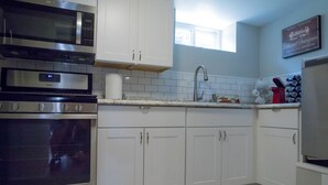 Una cocina moderna con armarios blancos, electrodomésticos de acero inoxidable y un salpicadero de azulejos.
