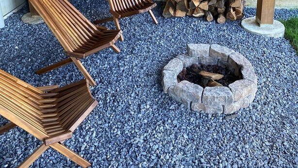 Un espacio al aire libre con sillas de madera y un hogar de piedra.