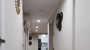 Un pasillo con piso de madera, paredes blancas y adornos en la pared.