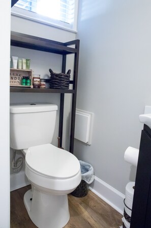 Bathroom features a toilet, toiletries, and a woven basket on a shelf.